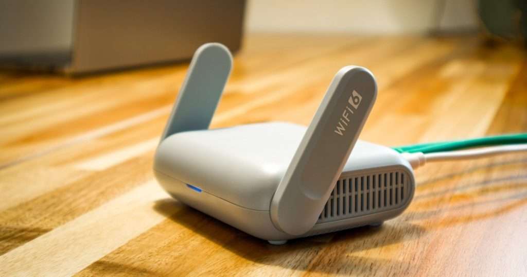 AdGuard Home: router compacto con wifi 6 y dos antenas plegables sobre un escritorio de madera, conectado por cable a la red