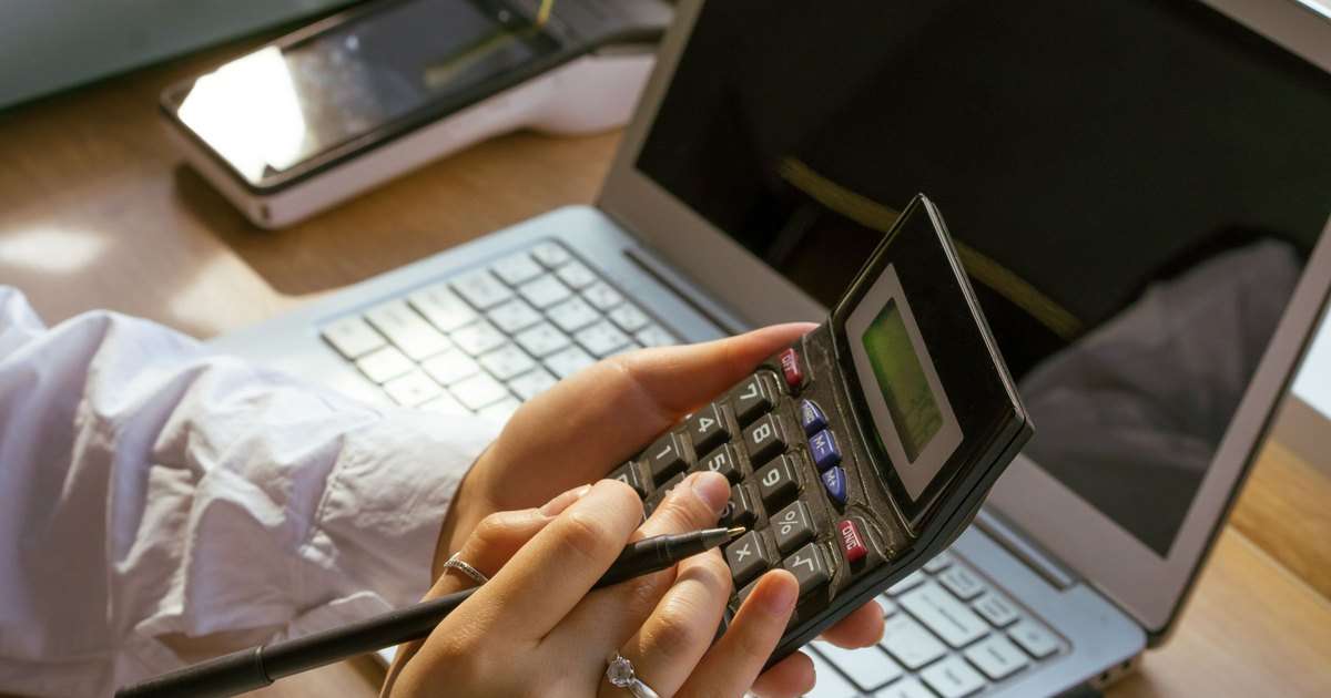 Licencias de Veeam: una persona calcula con una calculadora frente a un portátil cuántas instancias necesita