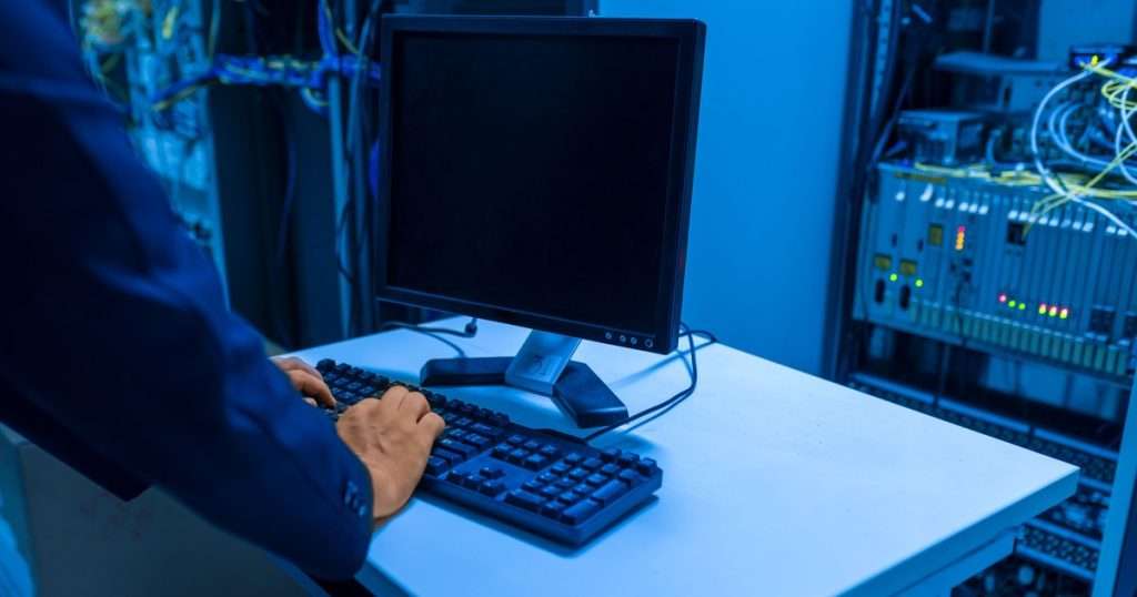 Administrador de red en la consola de un cuarto de comunicaciones, junto al rack de equipos, el puesto donde se nota la elección pfSense vs OPNsense