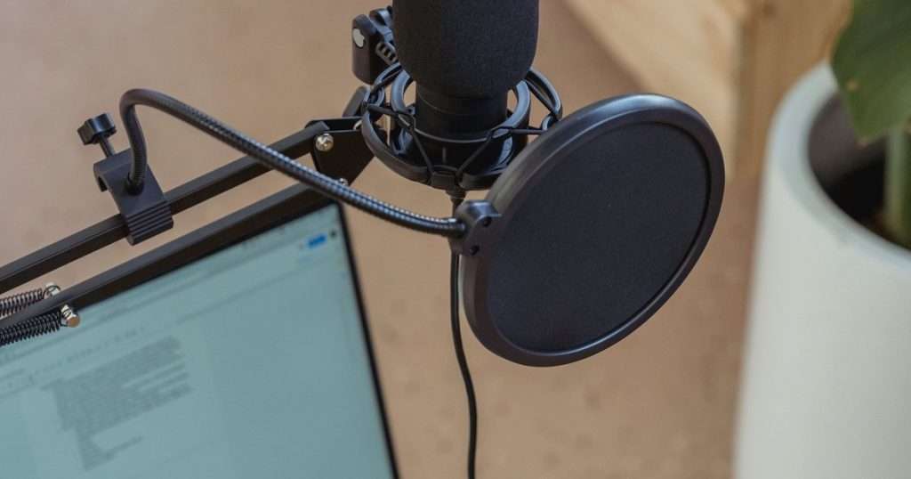 Dictar en Word: un micrófono de estudio con filtro antipop frente a un portátil que muestra un documento de texto