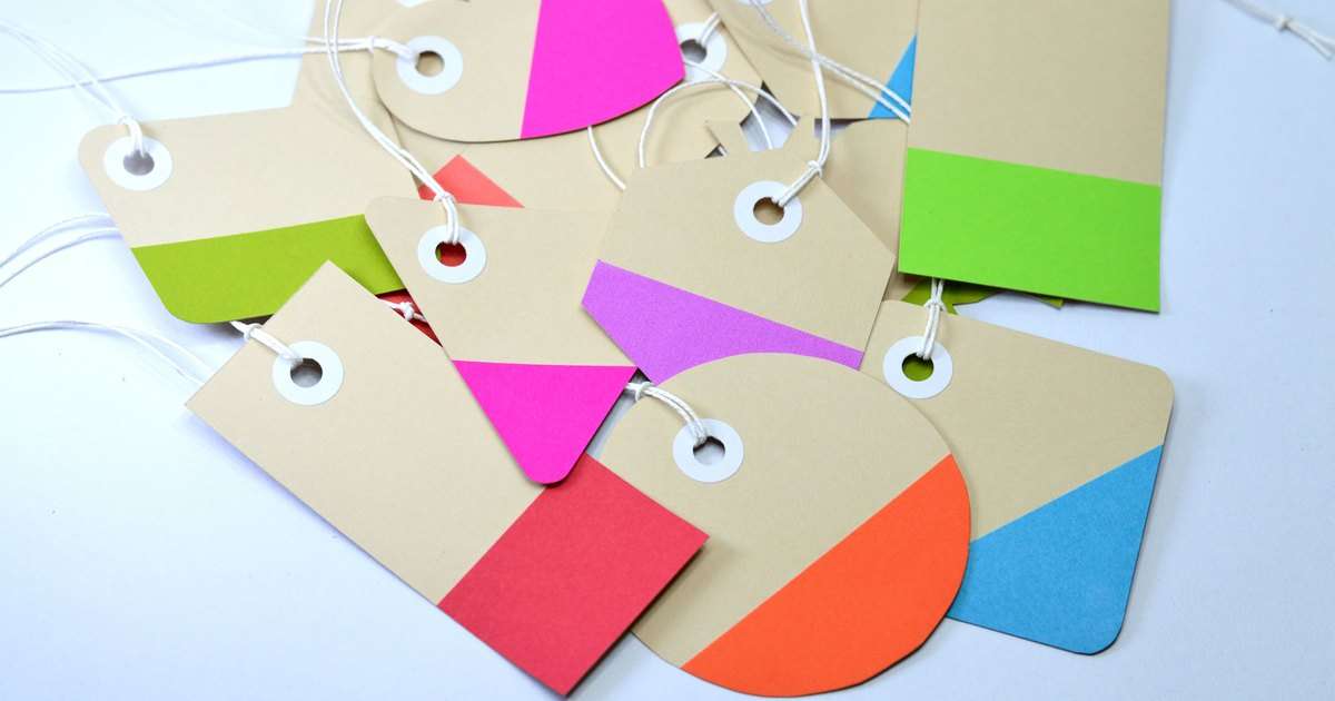 Etiquetas en Gmail: etiquetas colgantes de cartulina con franjas de colores distintos, amontonadas sobre una mesa blanca