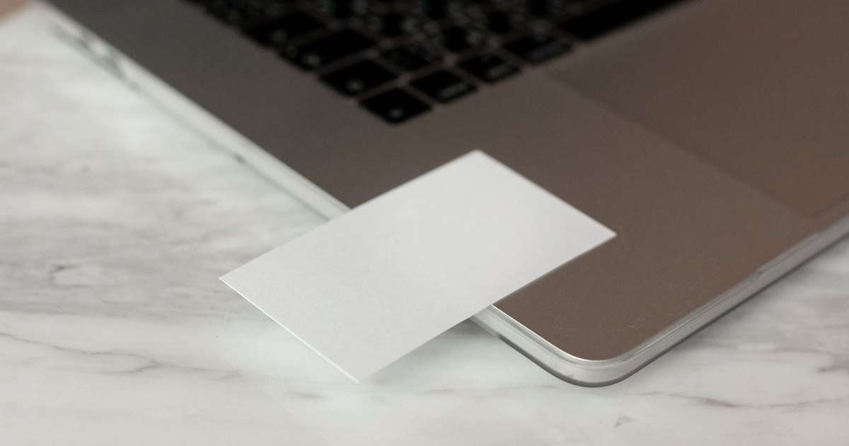 Firma en Gmail: tarjeta de presentación en blanco apoyada sobre un portátil abierto, encima de una mesa de mármol