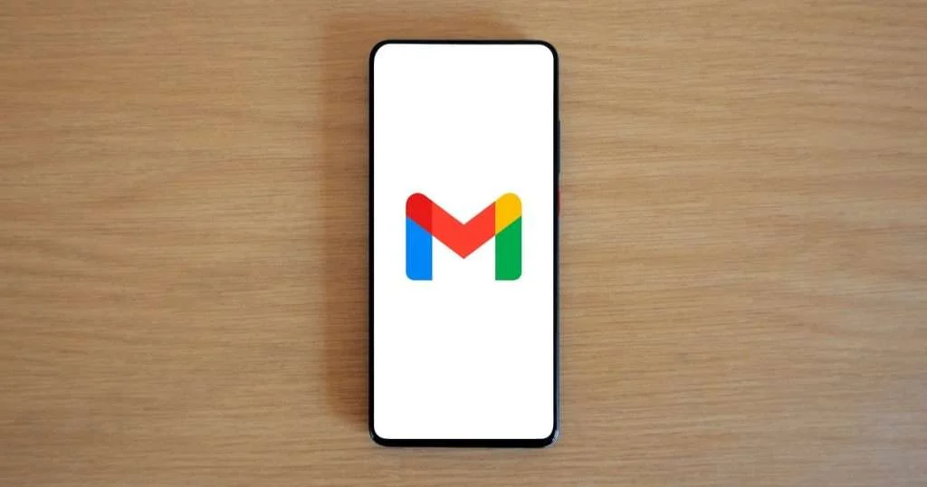 Liberar espacio en Gmail: un teléfono sobre un escritorio de madera con el logotipo de Gmail en la pantalla