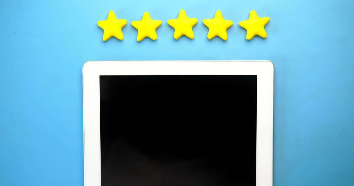 Microsoft Forms: cinco estrellas amarillas de valoración en fila sobre una tableta blanca con la pantalla apagada, en un fondo azul, como una pregunta de calificación de una encuesta