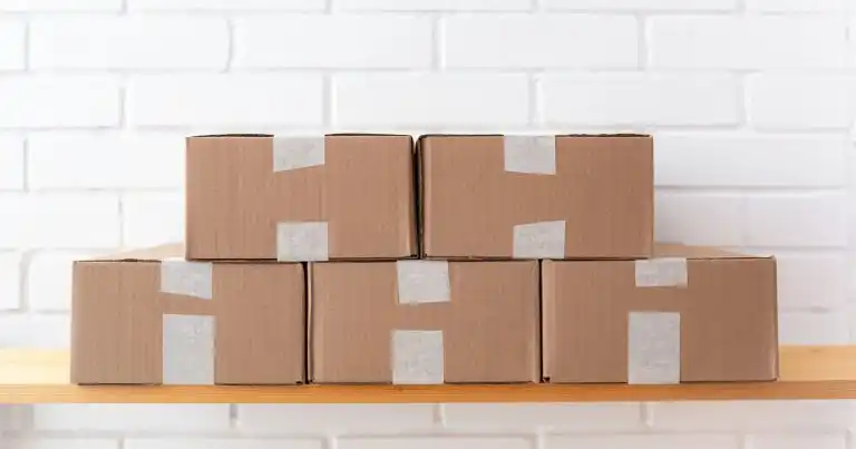 Winget, el administrador de paquetes de Windows: cinco cajas de cartón iguales, cerradas con cinta, ordenadas sobre una repisa de madera frente a una pared de ladrillo blanco