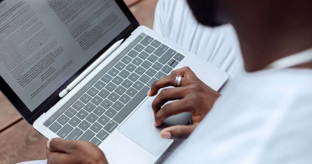 Word avanzado: persona que revisa un documento de texto largo, a dos páginas, en la pantalla de un portátil, con un lápiz digital apoyado sobre el teclado